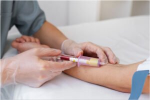 A phlebotomist using a Vacutainer to draw blood from a patient’s arm